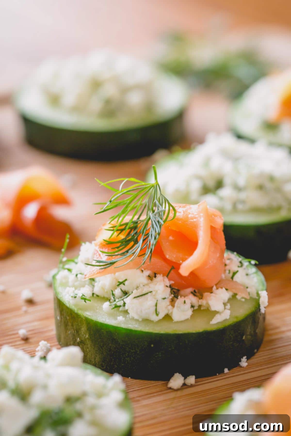 A vibrant smoked salmon cucumber bite on a wooden serving platter, garnished with fresh dill.
