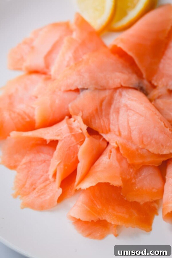 Cold vs Hot Smoked Salmon: A Deep Dive 5 Close-up of thin, glistening slices of cold-smoked salmon, highlighting its smooth, delicate texture and vibrant pink hue.