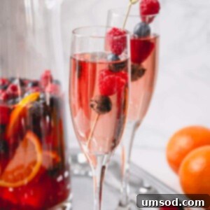 Sweet Summer Moscato Sangria 5 Moscato sangria in a champagne glass garnished with raspberries and blueberries.