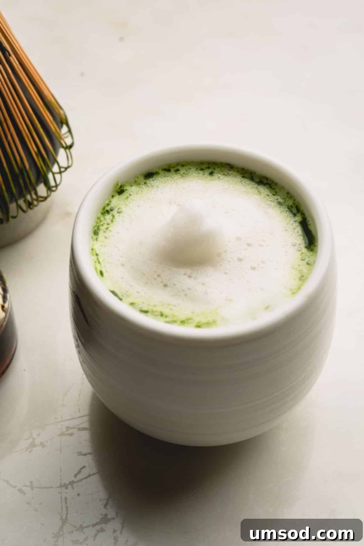 Mastering the Matcha Latte 4 A small cup of matcha latte, topped with a delicate layer of white foam, ready to be enjoyed.