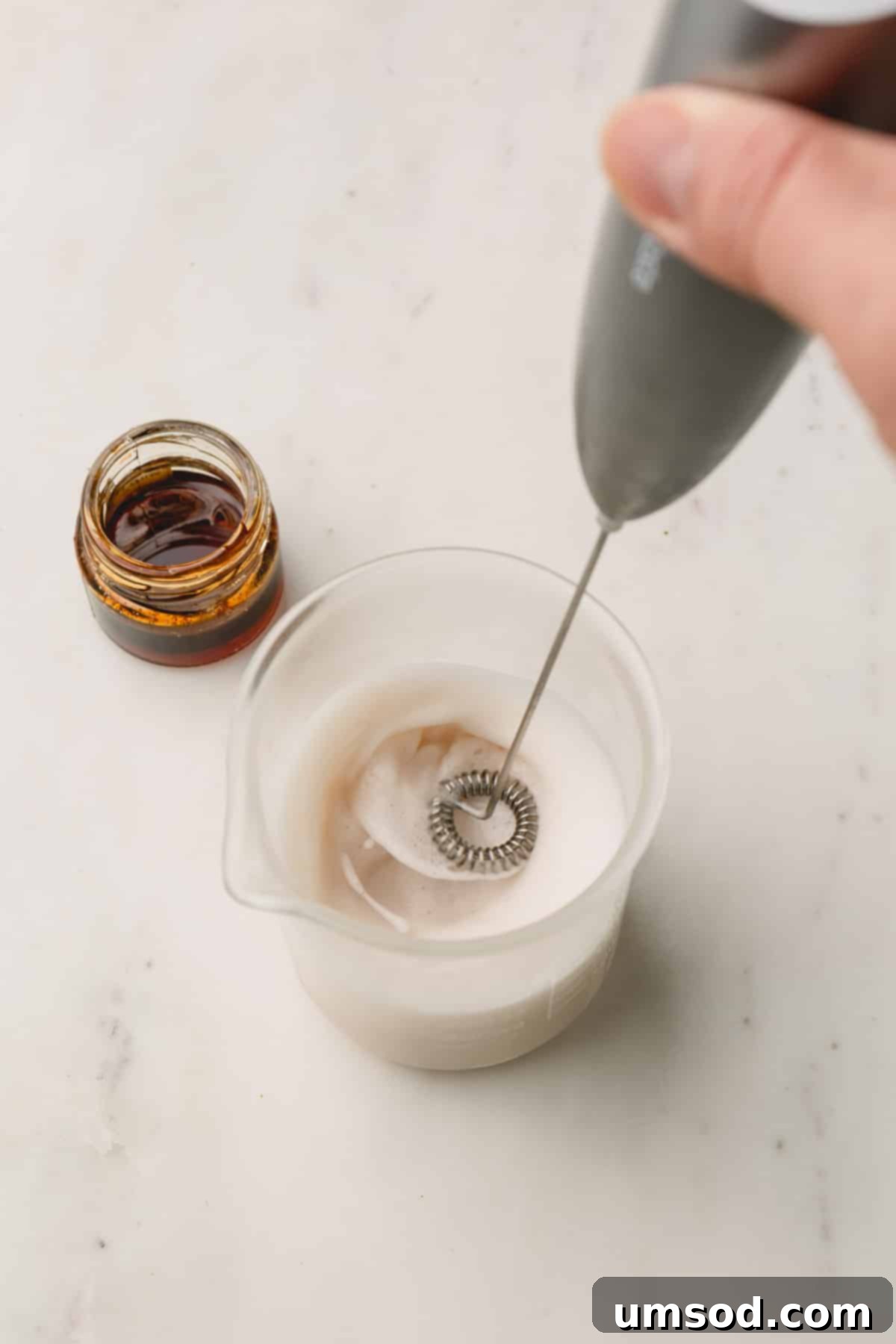 Mastering the Matcha Latte 8 A close-up of milk being frothed in a glass with a handheld milk frother, creating a rich and airy foam.