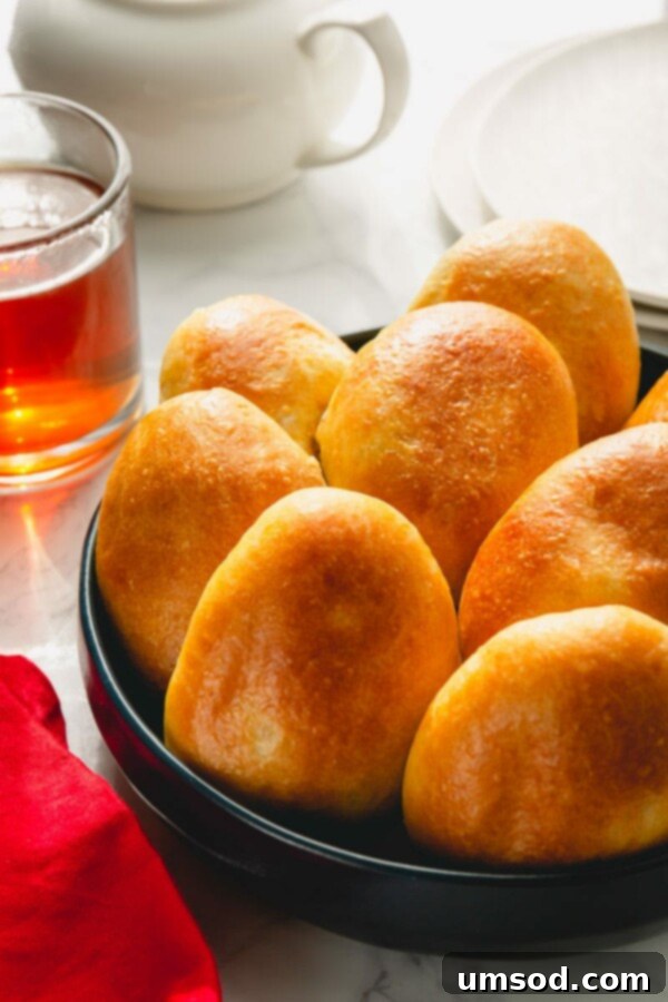 Traditional Russian Baked Meat Pirozhki 6 A plate of freshly baked pirozhki, one cut open to reveal the mashed potato and beef filling.