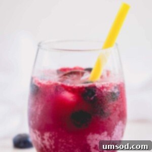 A refreshing glass of homemade sparkling blueberry lemonade with a yellow straw.