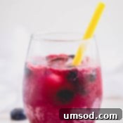 A close-up of a glass of blueberry lemonade, showing the vibrant color and garnishes.