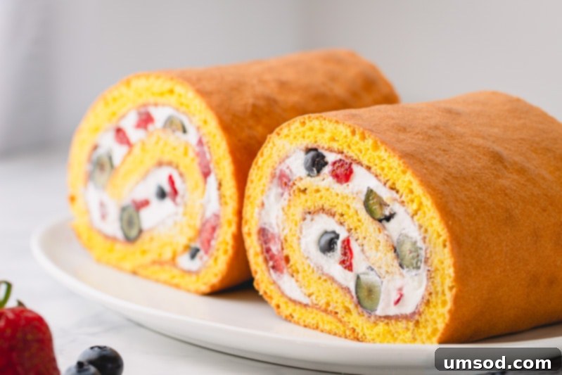 A beautifully rolled Berrylicious Roll Cake, showcasing a perfect, crack-free spiral with fresh fruit and whipped cream filling, ideal for any occasion.