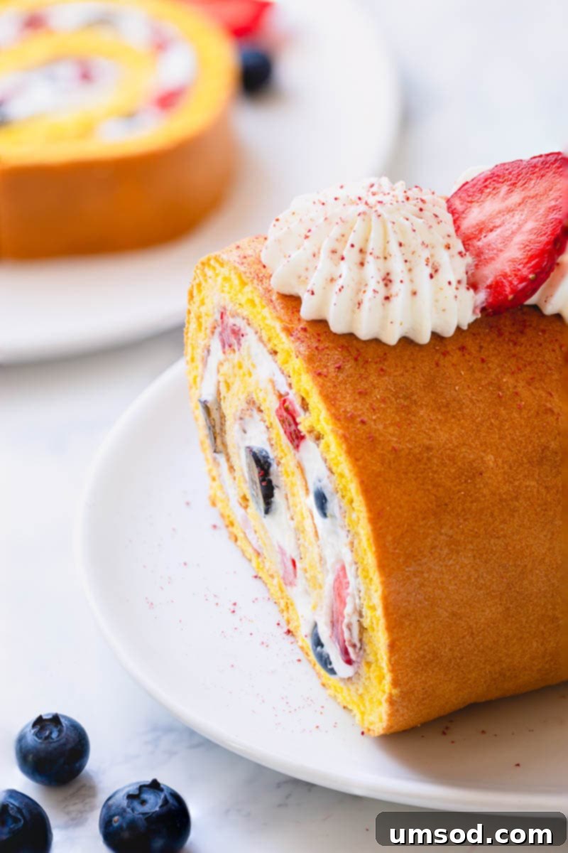 A close-up view of a perfectly sliced simple roll cake, revealing the beautiful spiral of fluffy cake, rich whipped cream, and fresh berries – an ideal last-minute dessert solution.