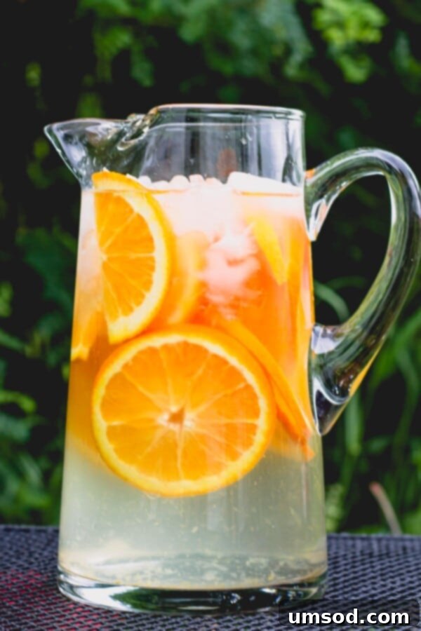 Three Ways to Refresh with Infused Water 5 A glass pitcher of water infused with thinly sliced oranges and ice.