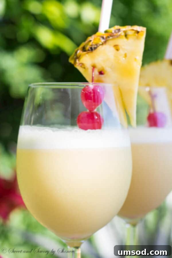 Ingredients for Pina Colada with orange juice laid out on a table: pineapple juice, rum, cream of coconut, ice, and oranges