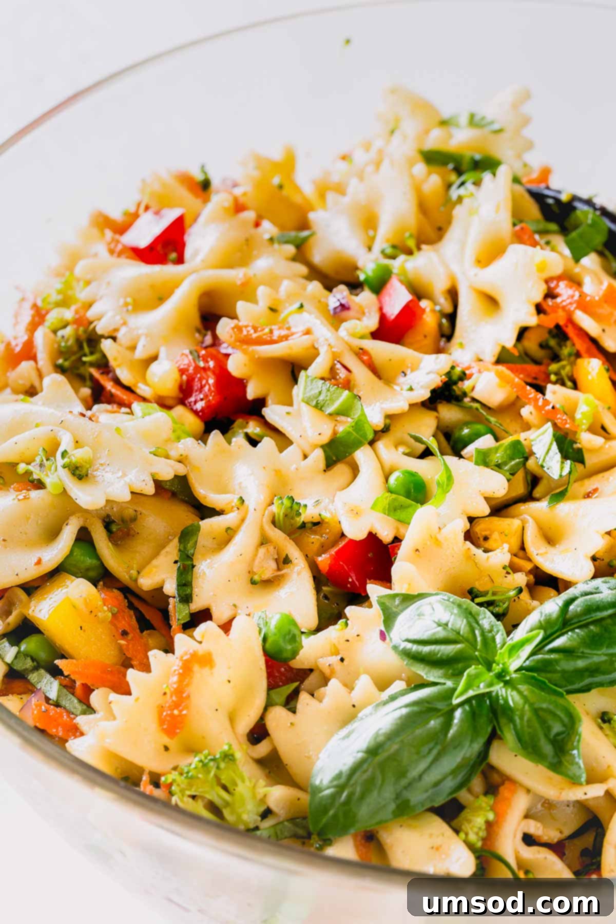 A large serving bowl filled with colorful veggie pasta salad, ready to be served.