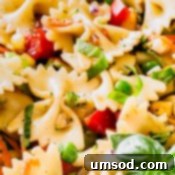 A bowl of vibrant veggie pasta salad with farfalle pasta, bell peppers, broccoli, and a balsamic dressing.