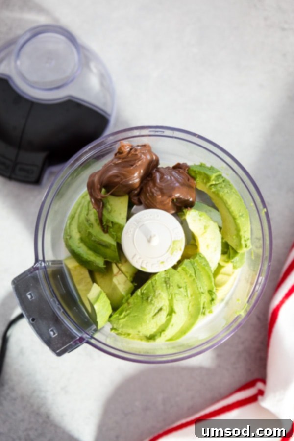Ingredients for avocado chocolate mousse laid out: half an avocado, almond milk, cocoa powder, maple syrup, and Nutella.