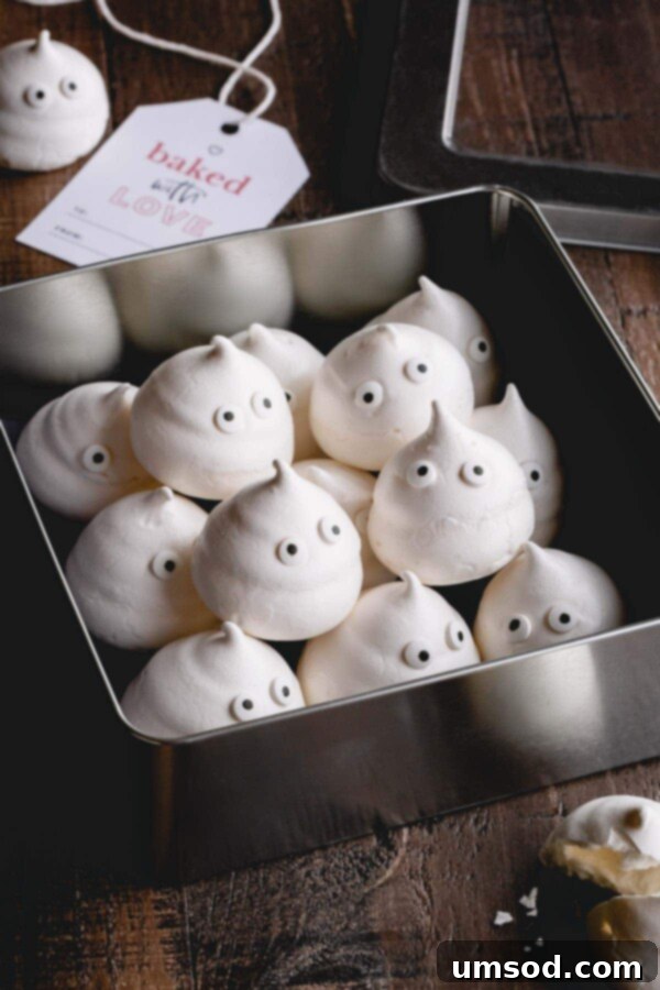 Ghostly Meringue Delights 3 A tray filled with rows of meringue ghosts, some with candy eyes, demonstrating the consistent piping and light texture.