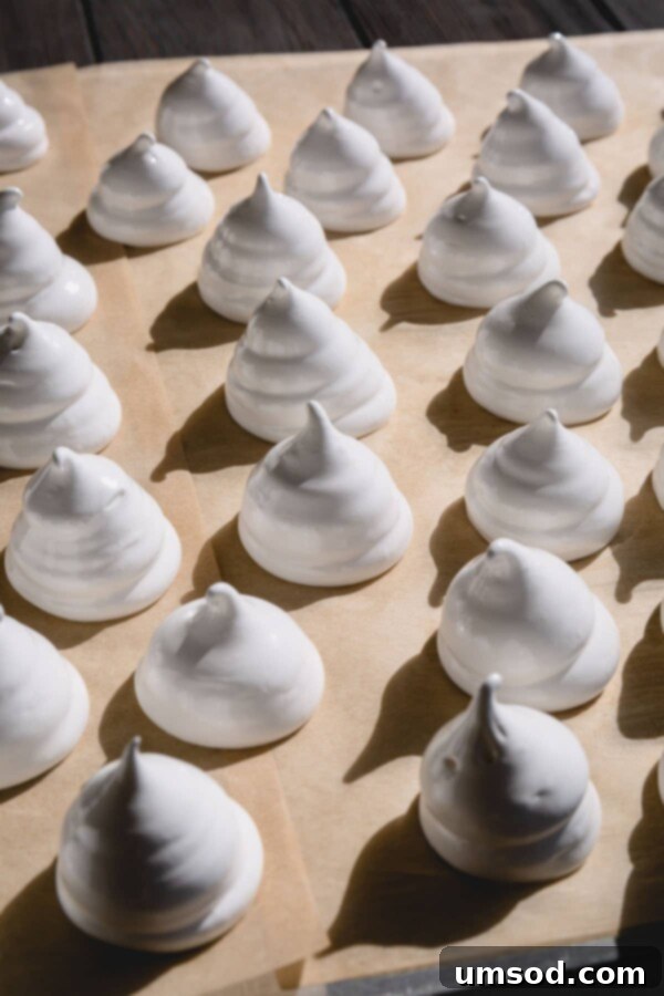 Ghostly Meringue Delights 5 A close-up of a meringue ghost with a neatly piped shape and two small candy eyes, ready for baking.