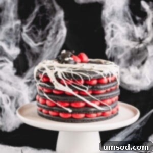 A 5-layer black macaron cake filled with red cream cheese frosting on a white cake stand.