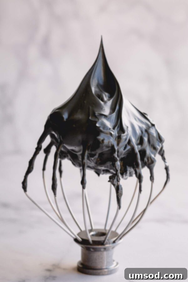 Perfectly whipped meringue showing stiff peaks and sharp ridges on a whisk.