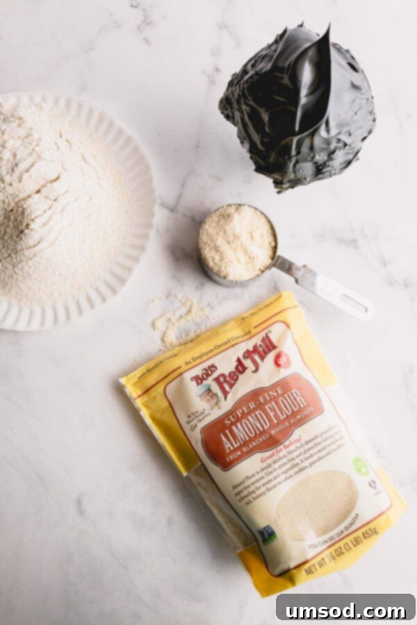 Sifting almond flour and powdered sugar through a fine-mesh sieve into a bowl.