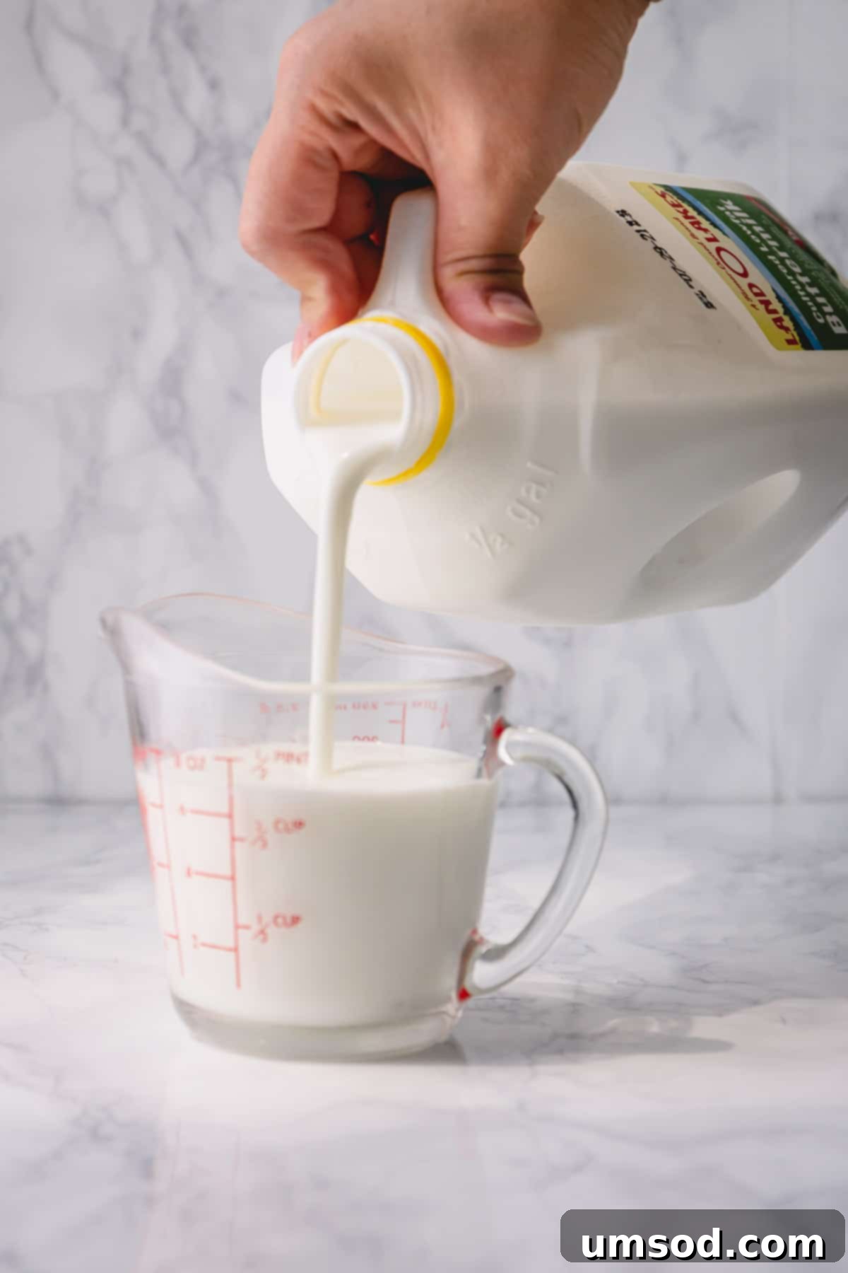 Freshly made buttermilk substitute being poured into a measuring cup, ready for use in a recipe.