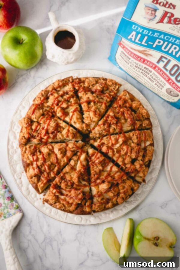 Sliced apple coffee cake drizzled with rich homemade caramel sauce, presented beautifully on a white serving plate, highlighting its moist texture and golden-brown streusel.