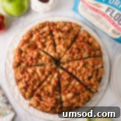 Overhead image of sliced apple coffee cake drizzled with caramel sauce on a white serving plate.