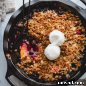 Quick Fruit Crisp 11 A skillet full of fruit crisp topped with two scoops of vanilla ice cream.