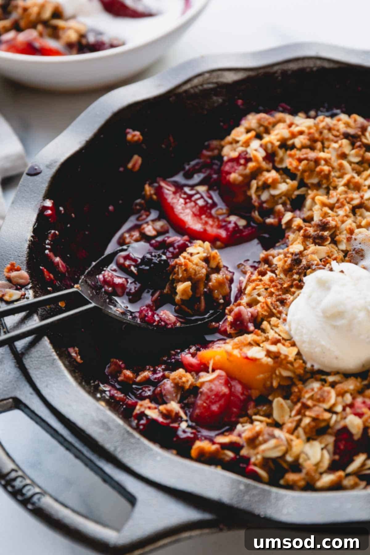 Quick Fruit Crisp 8 A spoon scooping up a portion of easy fruit crisp topped with vanilla ice cream.