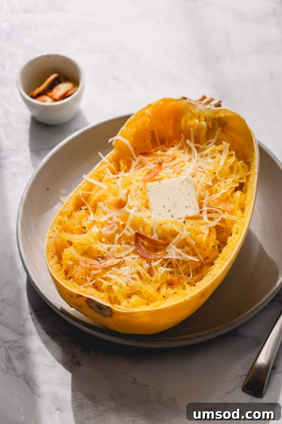 Spaghetti Squash Made Easy: Two Delicious Ways 2 Half of baked spaghetti squash with butter and parmesan cheese.
