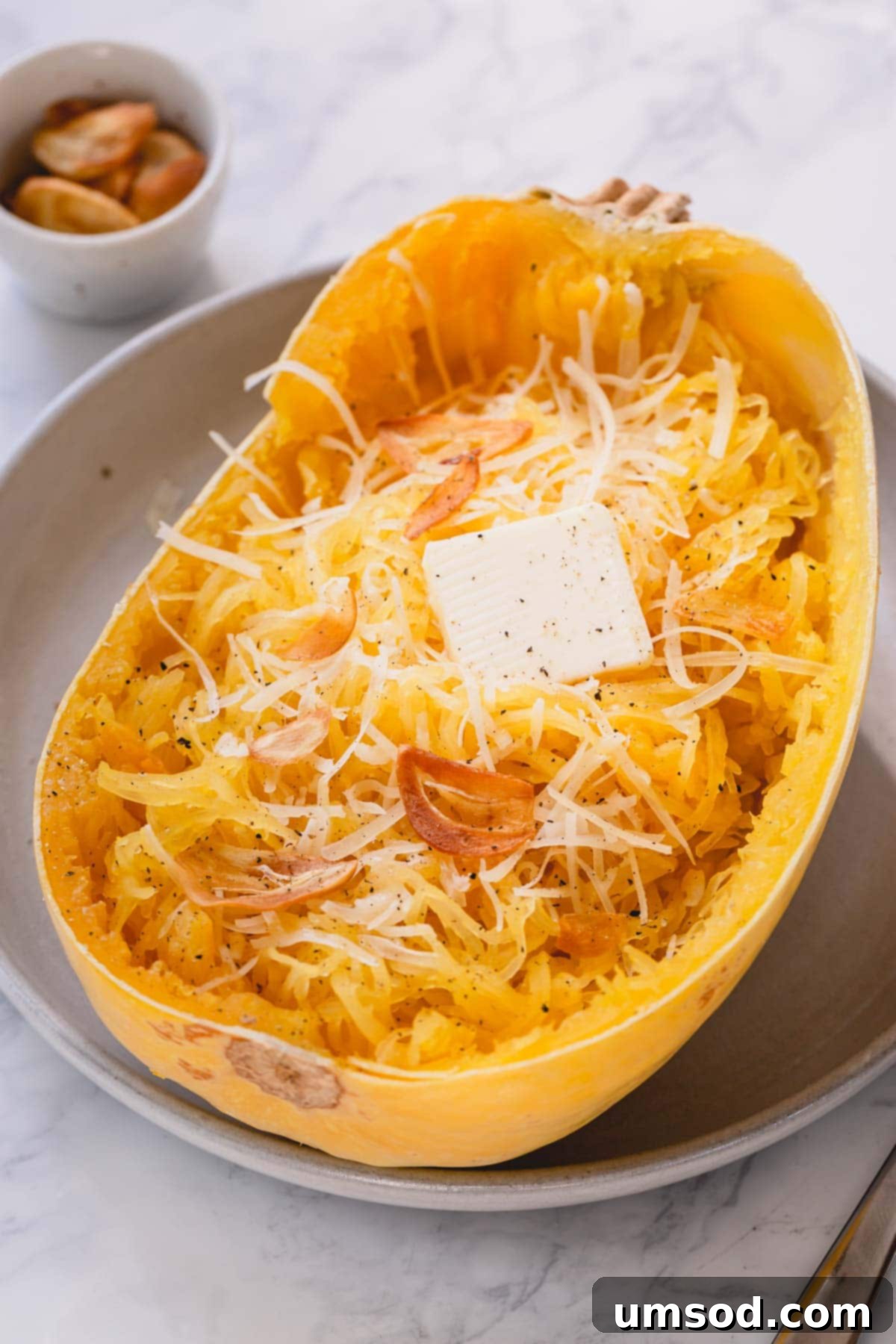 Spaghetti Squash Made Easy: Two Delicious Ways 7 Half of baked spaghetti squash with butter and parmesan cheese.