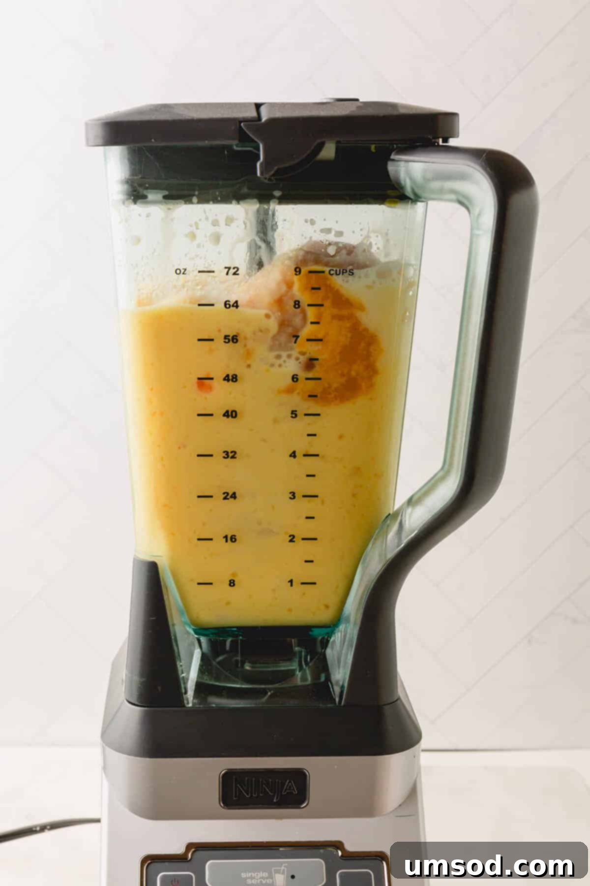 A blender with a coconut orange Julius drink mixture in it.
