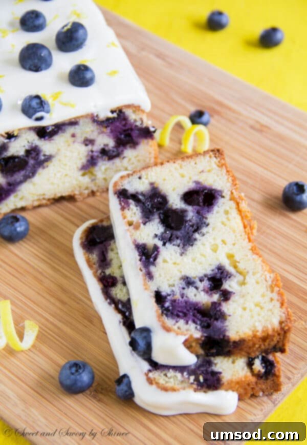 Zesty Lemon Blueberry Bake 2 A beautifully sliced blueberry lemon cake, generously loaded with fresh blueberries and adorned with a sweet and tangy lemon cream cheese frosting. The cake is light, tender, and presented as the perfect summer treat.