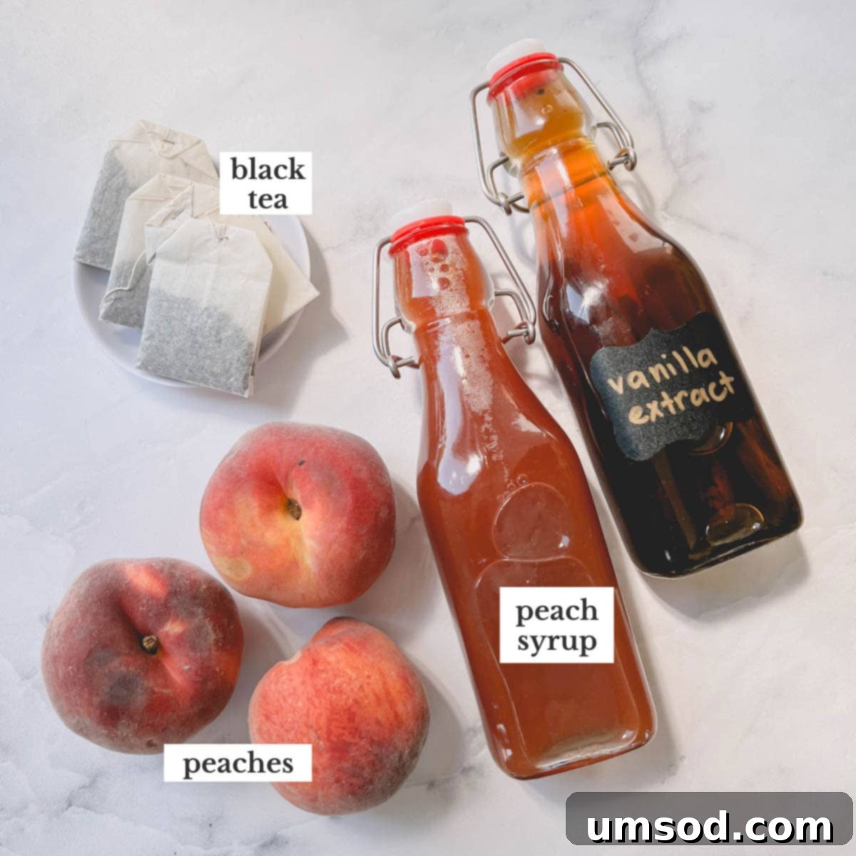 Peachy Keen Iced Tea 3 Individual ingredients for homemade peach iced tea laid out on a white surface, including fresh peaches, black tea bags, sugar, and water.