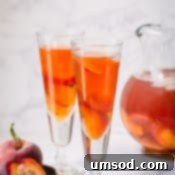 Peachy Keen Iced Tea 7 A close-up of a glass of peach iced tea garnished with fresh peach slices and a mint sprig.