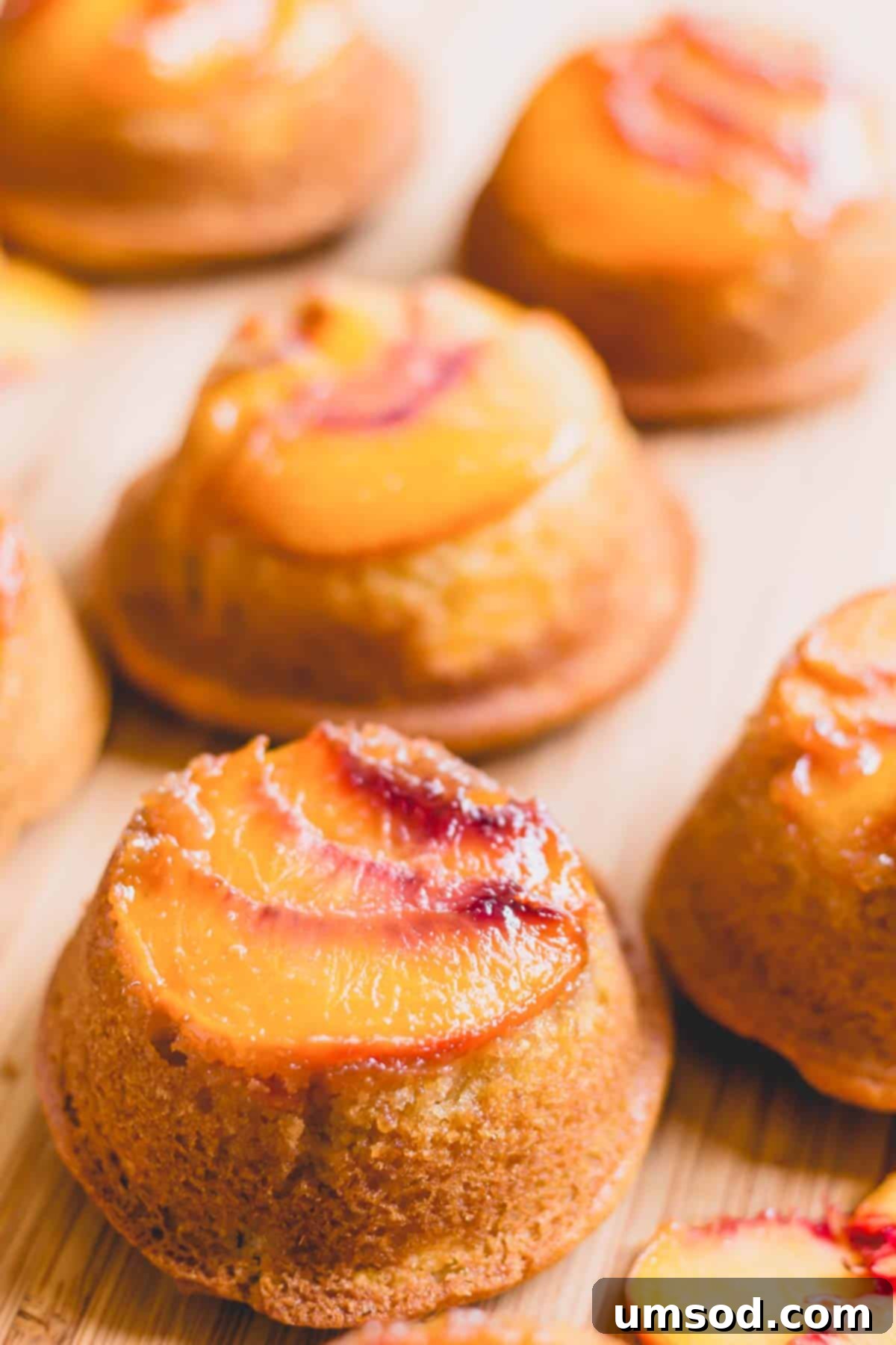 Caramelized Peach Upside-Down Cupcakes 6 Mini peach upside down cakes arranged artfully on a rustic wooden board, ready for serving.
