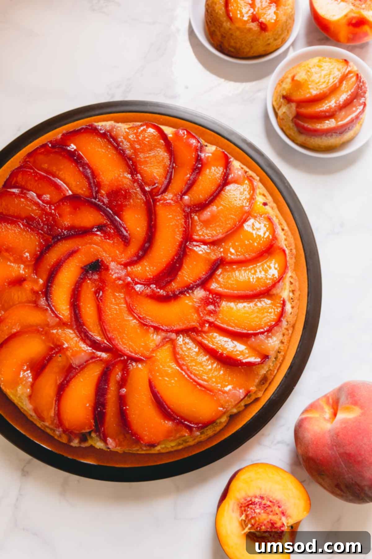Caramelized Peach Upside-Down Cupcakes 7 A beautiful round peach upside down cake on a larger serving plate, demonstrating the adaptability of the recipe from mini cakes to a full-sized dessert.
