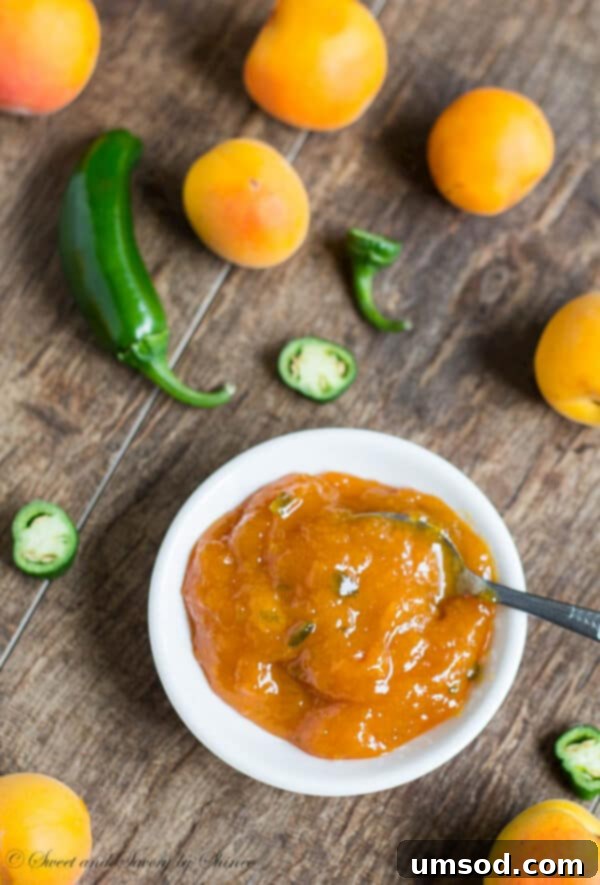Apricot jalapeño jam in a jar, visibly showing green flecks of jalapeño.