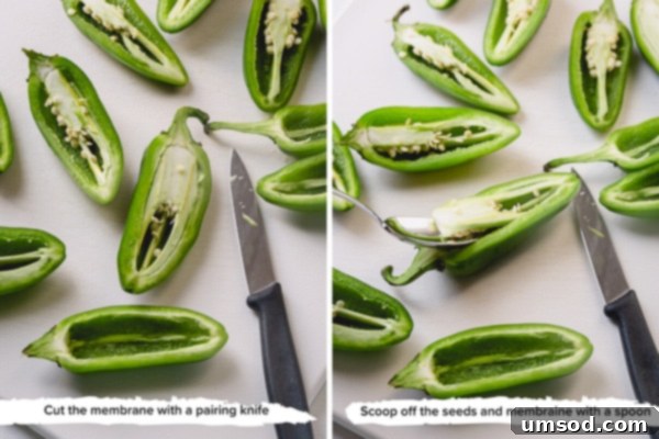 A cutting board with halved jalapenos, showing the removed seeds and ribs, ready for filling.