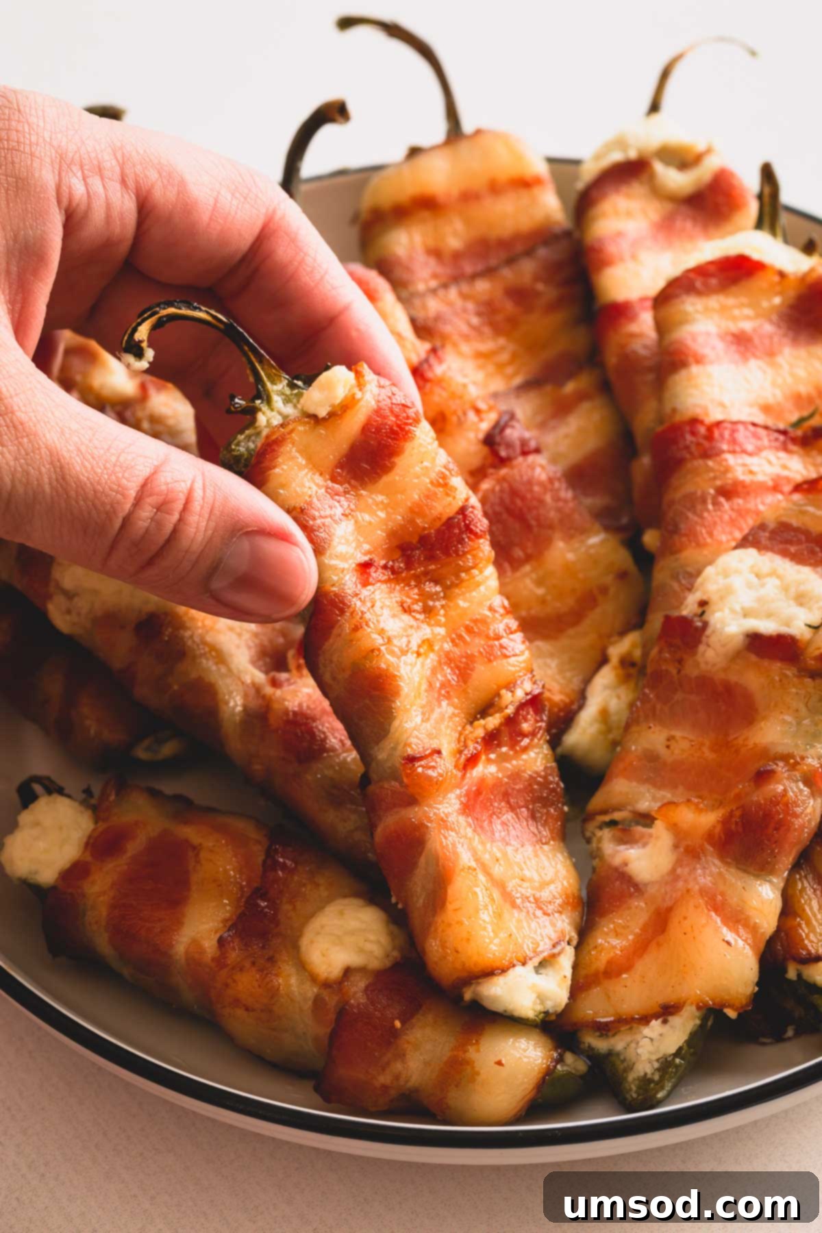 A beautiful platter filled with golden brown bacon wrapped jalapeno poppers, garnished for serving.