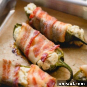 Cooked bacon jalapeno poppers on a baking sheet, ready to serve.