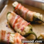 Cooked bacon jalapeno poppers on a baking sheet, ready for serving.