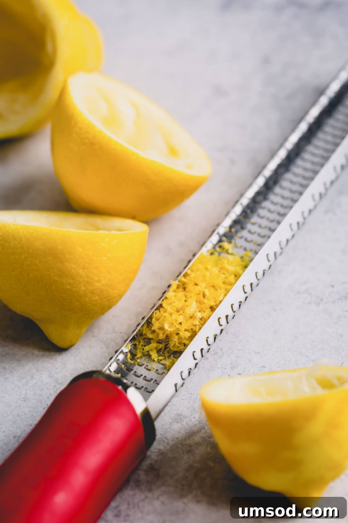 The Ultimate Lemon Handbook 5 Lemon zest being carefully scraped into a hand zester.
