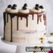 Black Forest cake with chocolate drizzle on a white cake platter.