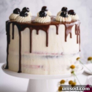 Black Forest cake with chocolate drizzle on a white cake platter.