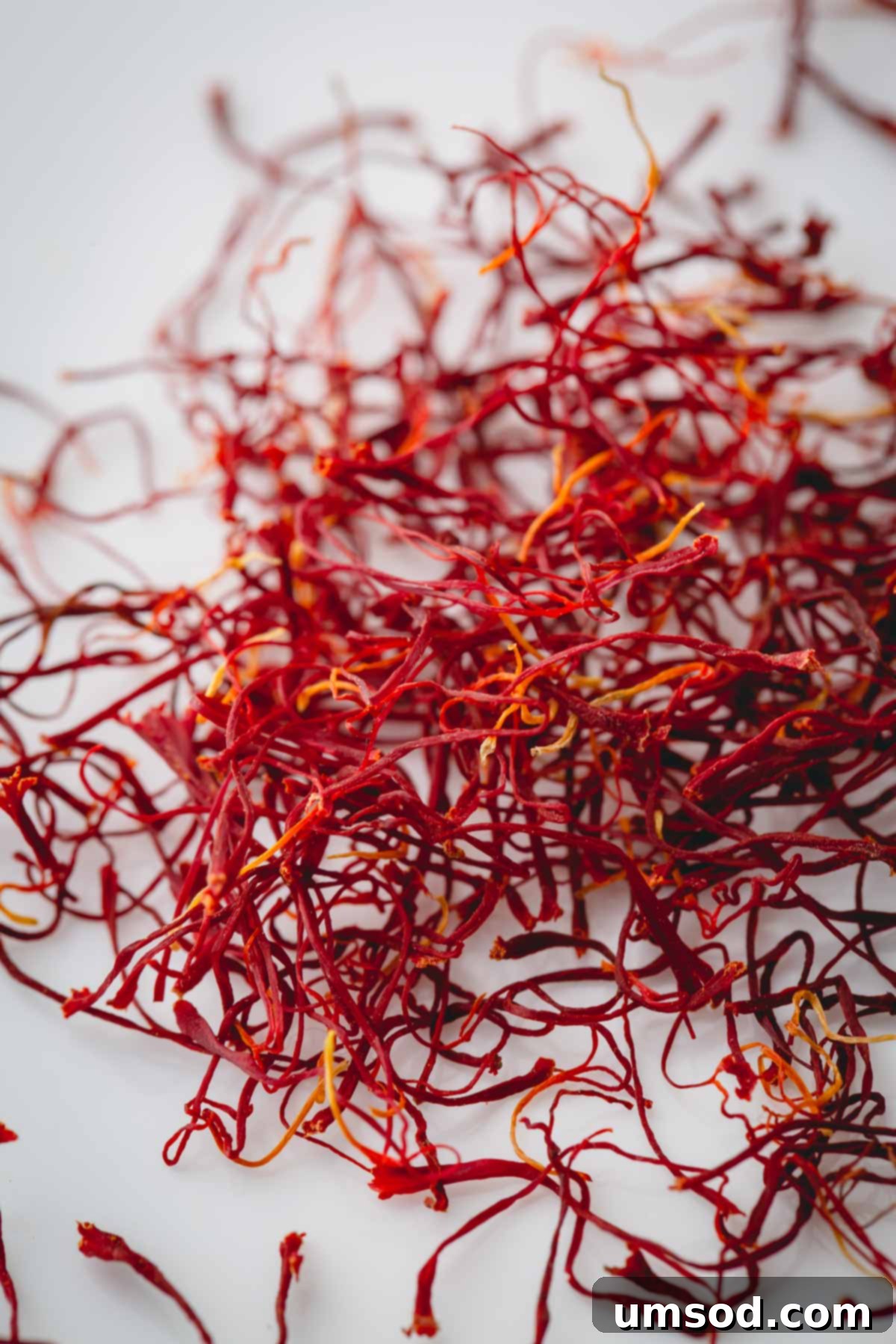 Saffron A Beginners Guide 2 Strands of vibrant red saffron on a pristine white background, showcasing its delicate texture.