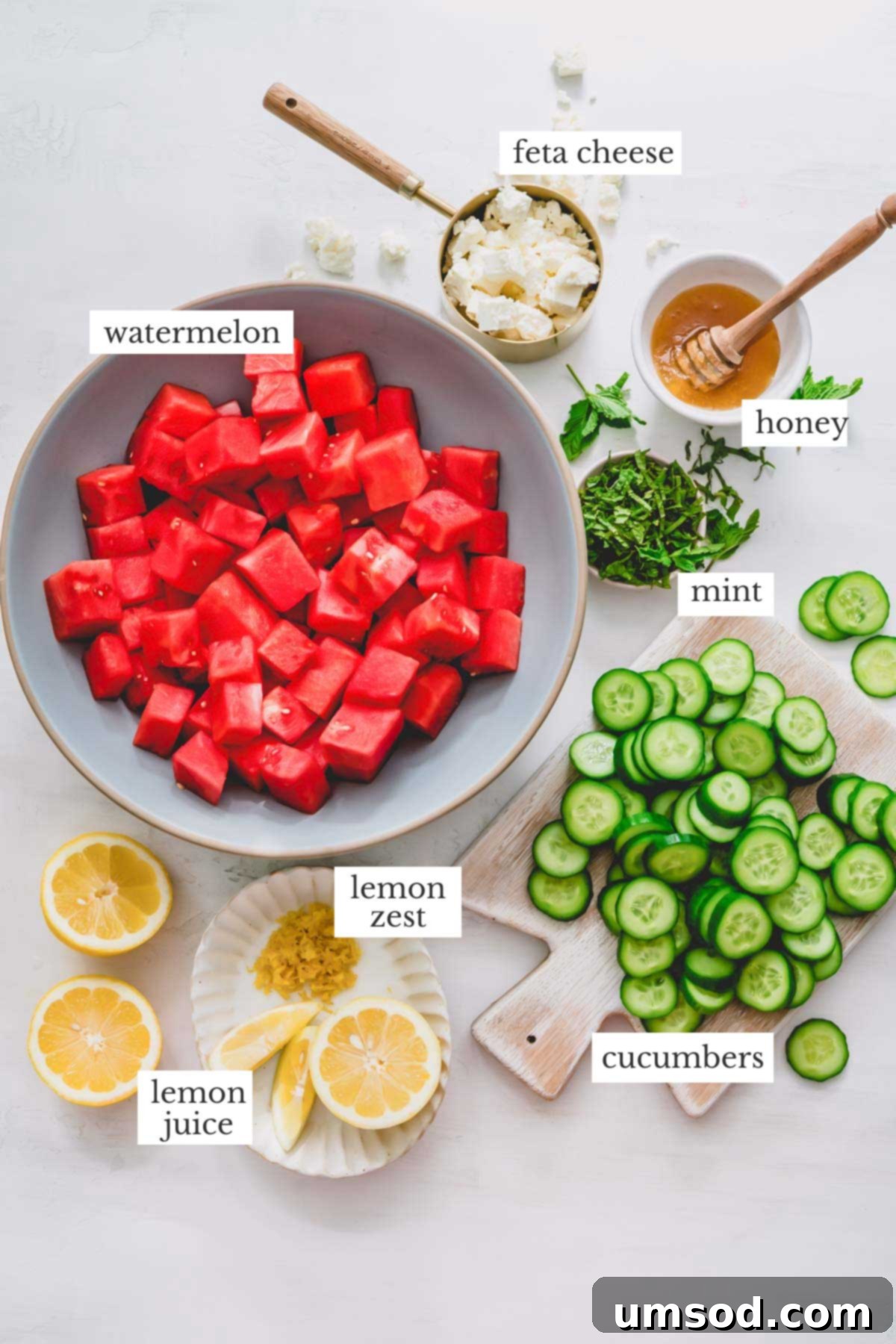 Fresh ingredients laid out for making watermelon feta salad, including cubed watermelon, cucumbers, feta, and mint.