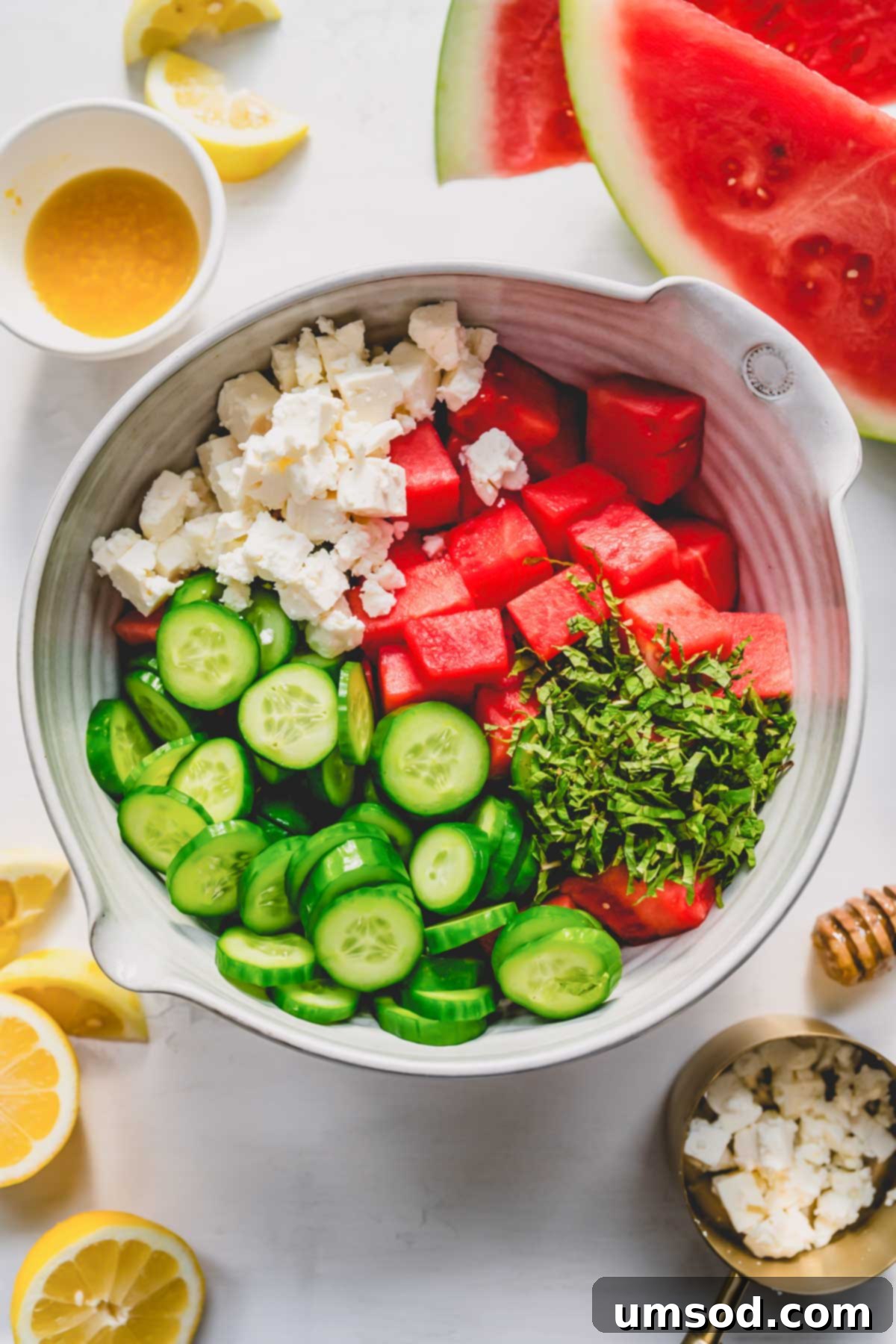 Watermelon, cucumbers, and feta cheese combined in a large mixing bowl, ready for dressing.