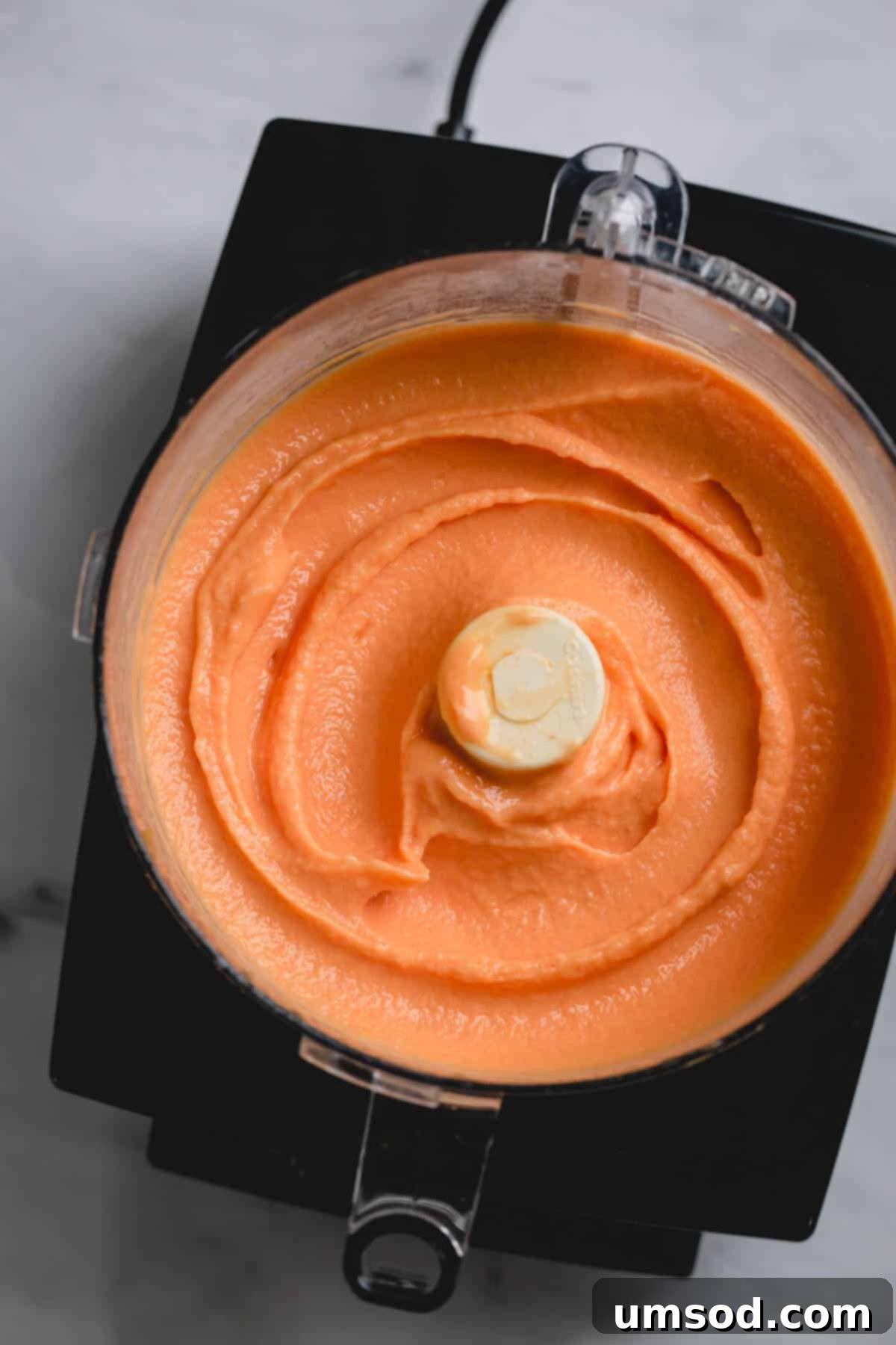 Golden Peach Dream 2 Smooth and creamy peach ice cream swirling in a large food processor bowl, ready to be scooped.