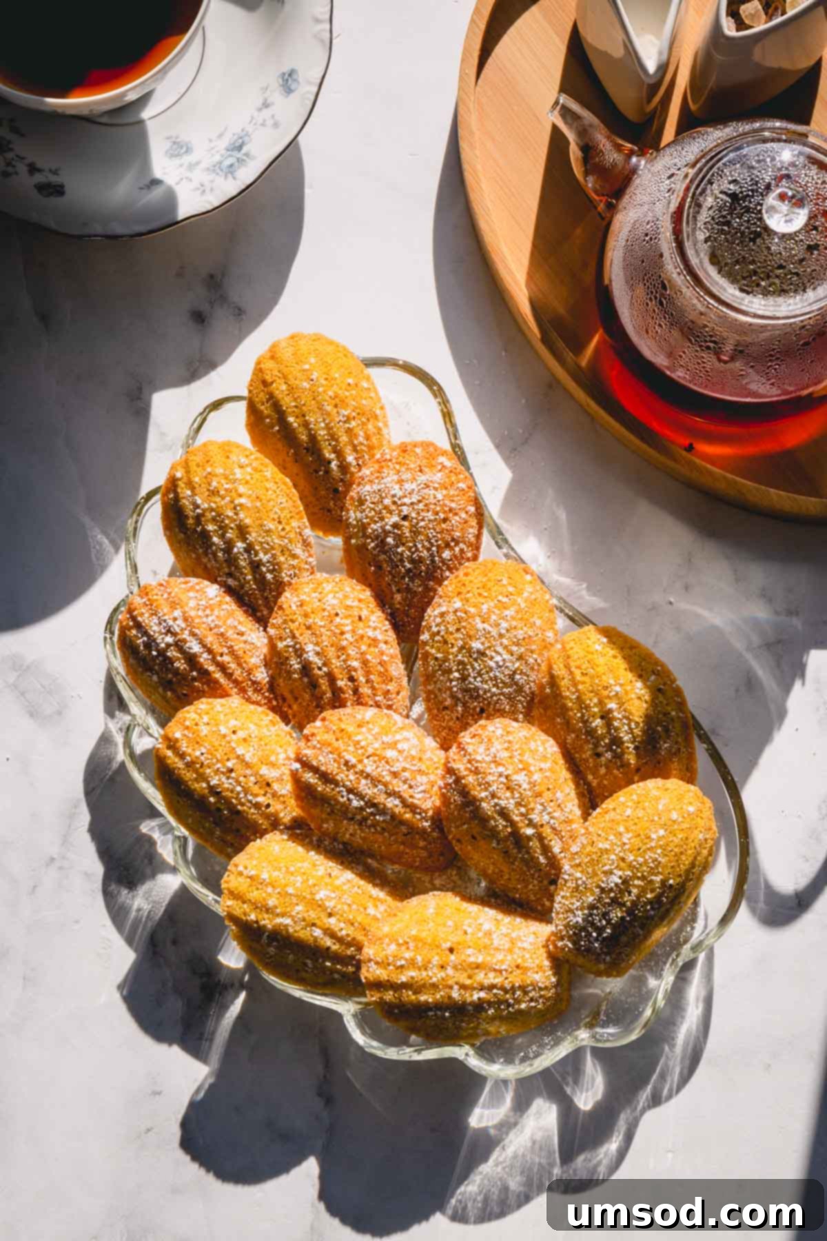 Zesty Bergamot Madeleines 2 A beautifully arranged plate of golden-brown Earl Grey Lemon Madeleines, showcasing their iconic seashell shape and delicate texture.