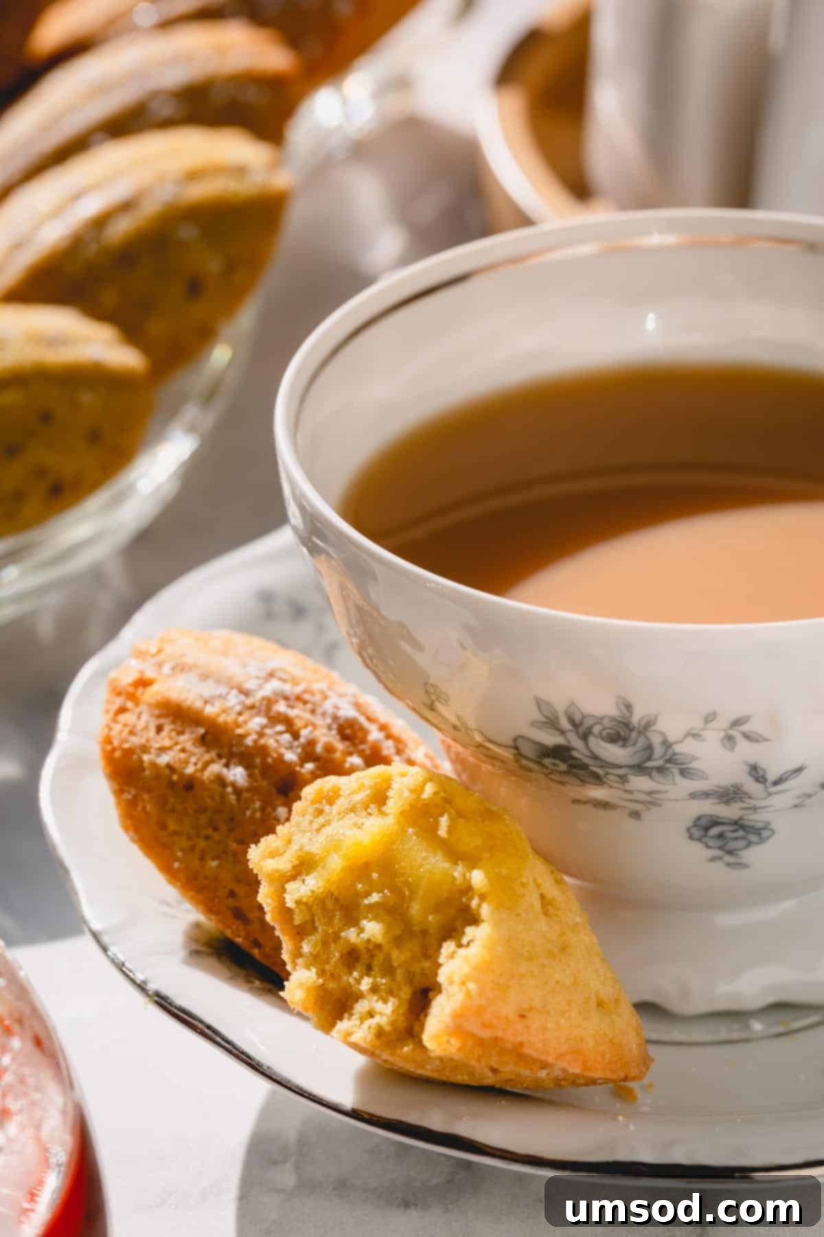 Zesty Bergamot Madeleines 3 A close-up shot of a baked lemon madeleine with a small bite taken out, clearly revealing its soft, light yellow interior and generous lemon curd filling.