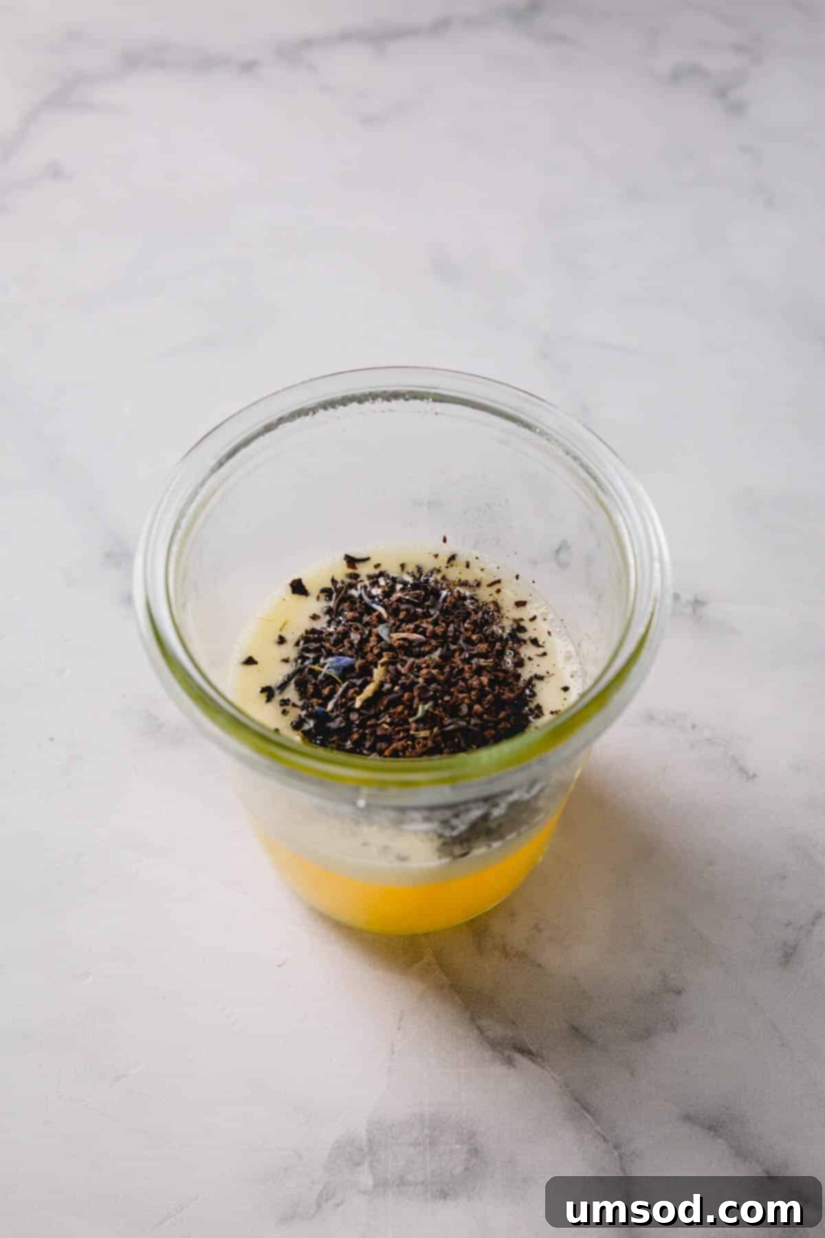 Zesty Bergamot Madeleines 5 Close-up image of Earl Grey tea leaves steeping gently in melted butter in a small saucepan, illustrating the crucial infusion process.