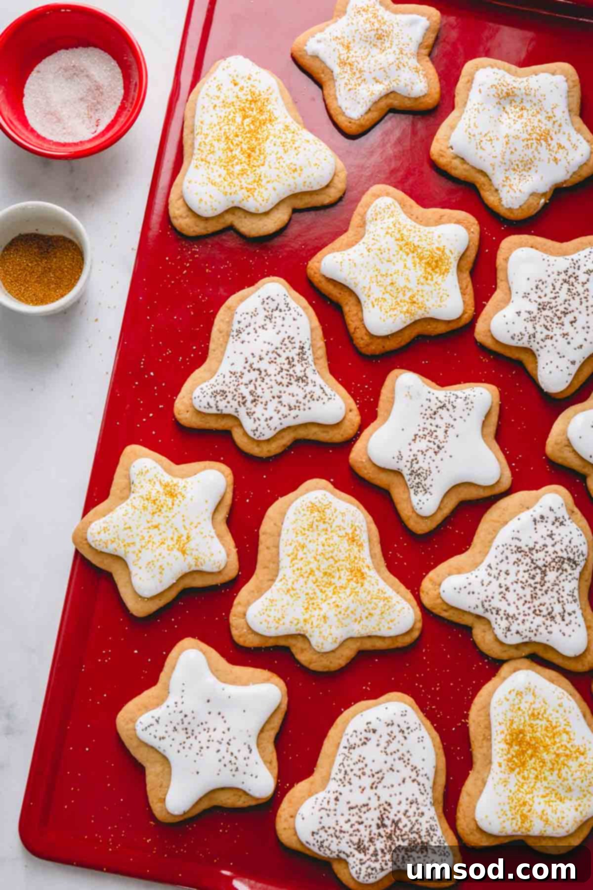 Beautifully frosted Christmas bell and star shaped cookies arranged on a vibrant red board, ready for the holiday season.