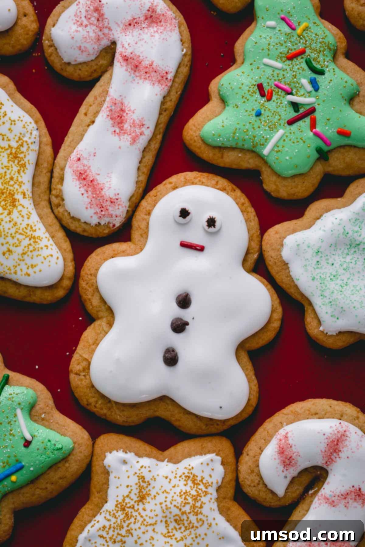 An assortment of classic Christmas shaped honey cookies artfully arranged on a striking red platter, awaiting their festive decoration.